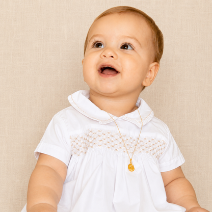 Bebé con bombacho Pablo de algodón blanco con smock bordado a mano, ideal para bautizos y ceremonias.